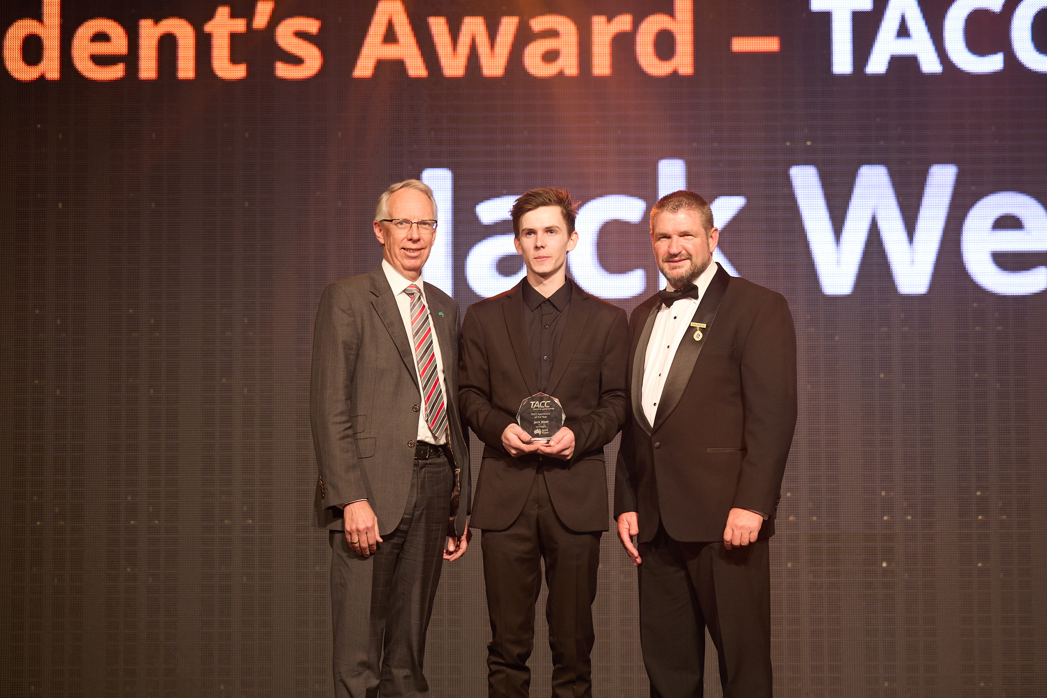 Jack West and 2 men on a stage accepting an award