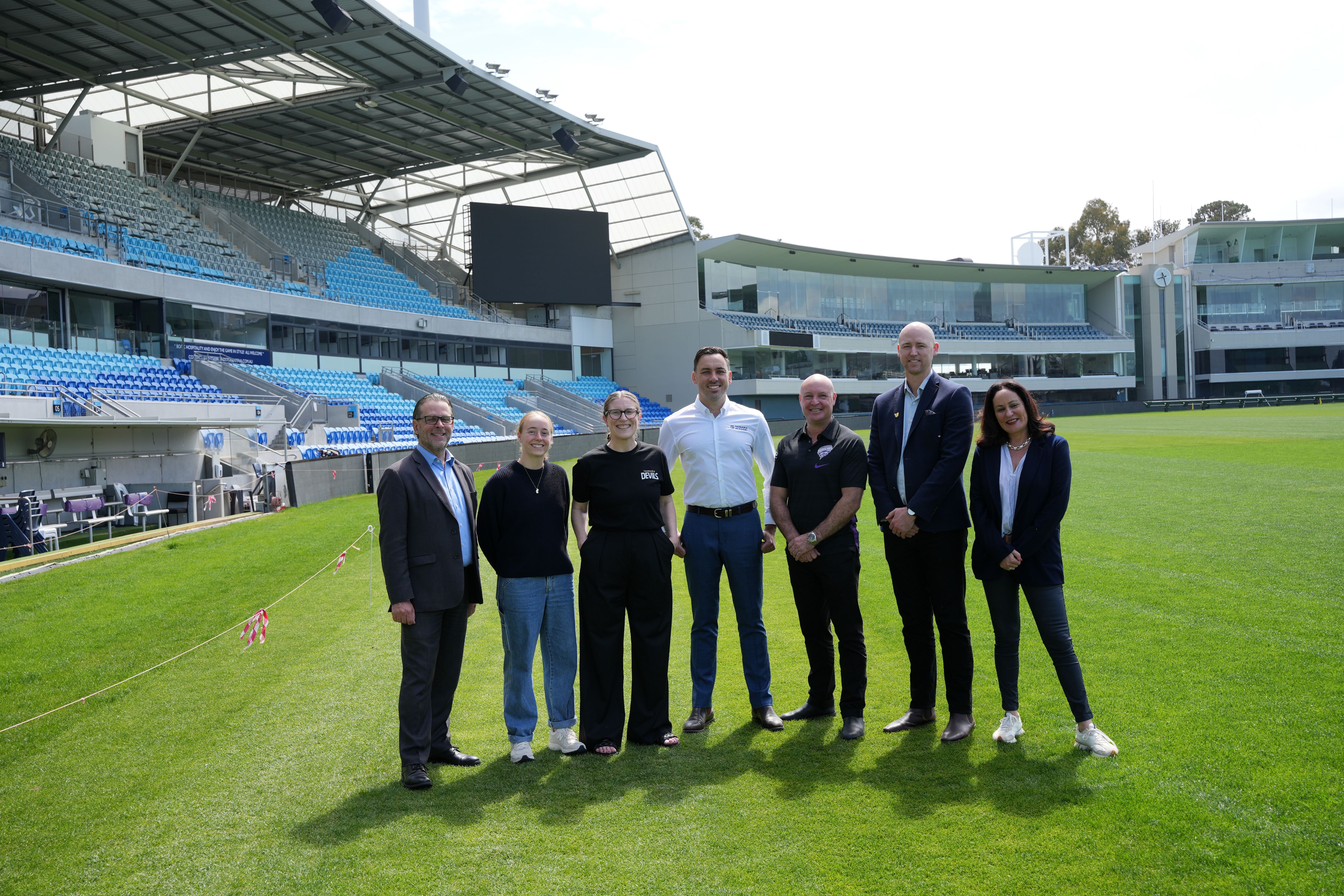 Group of people standing on the Bellerive oval with grandstands in background