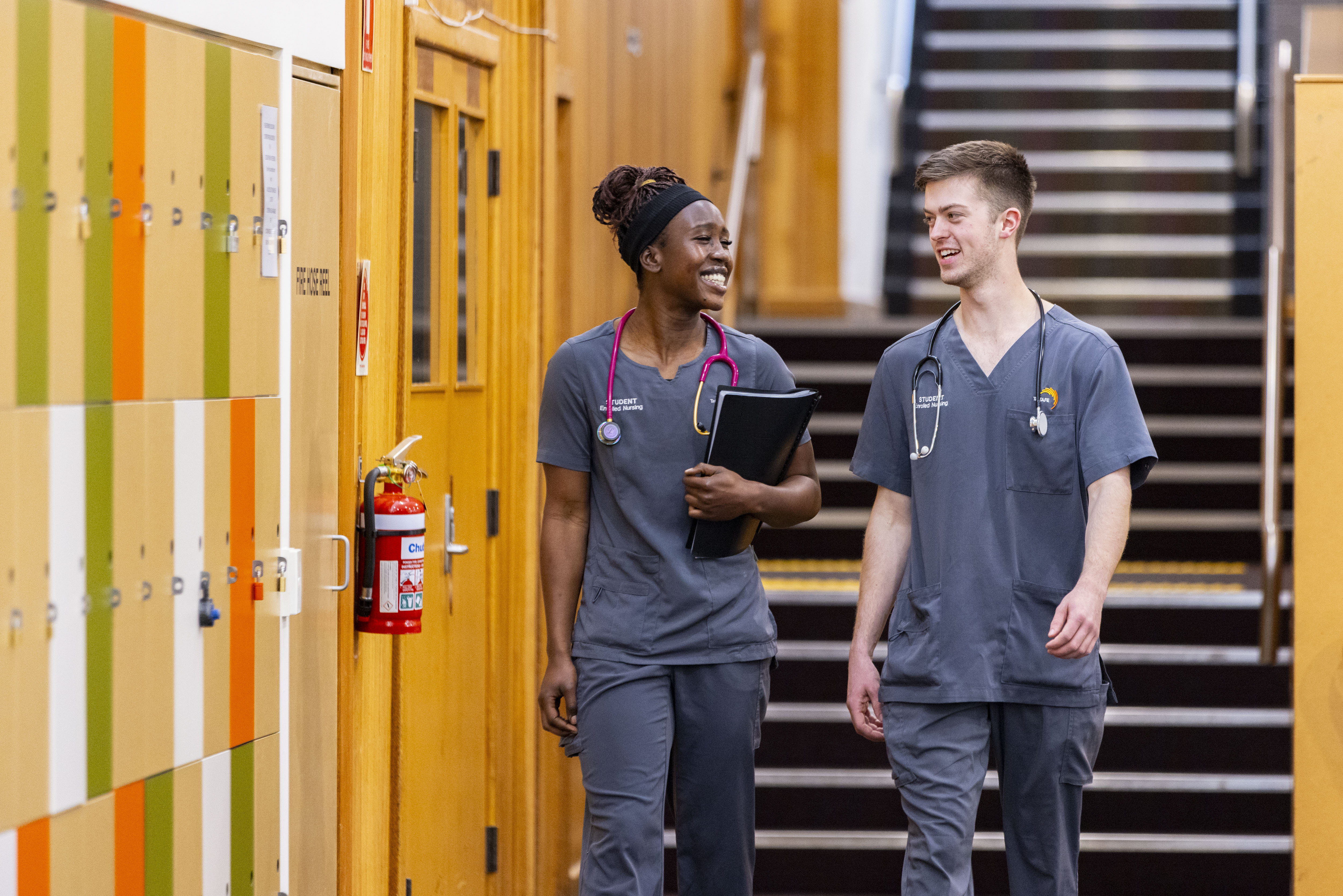 Nursign students walking down a corridor with colourful lockers in the background