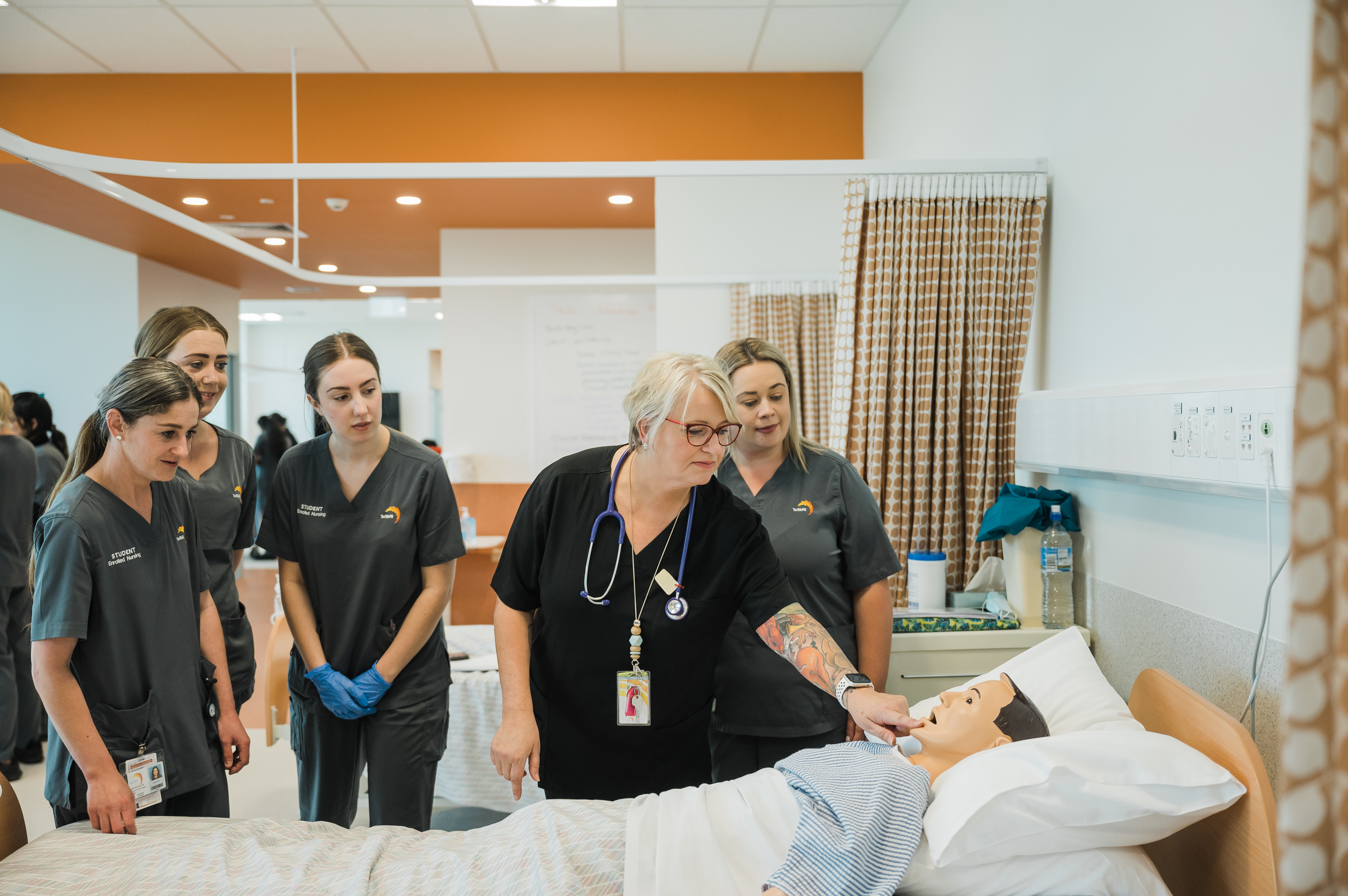 Nursing teacher and students with a dummy in simulated hospital 