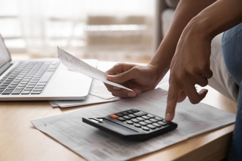 hands on a table with a laptop, papers and a calculator