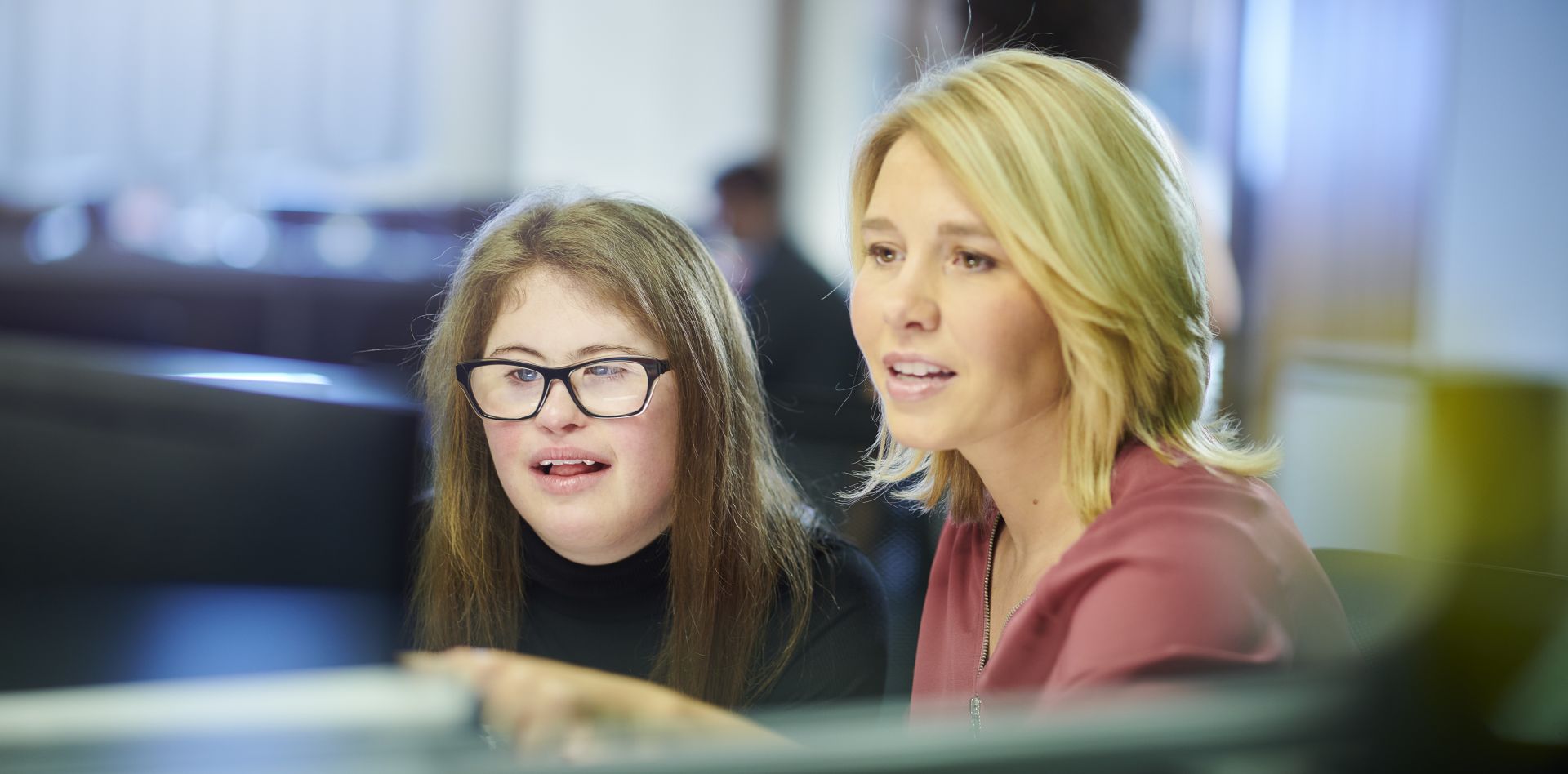 Disability support worker with client at a desk pointing to the computer screen