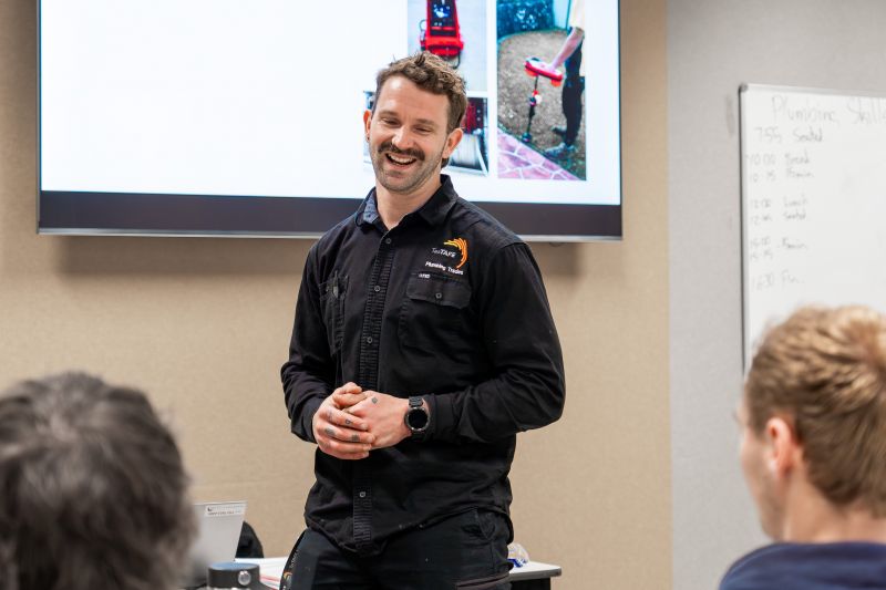 Plumbing teacher laughing at the front of the classroom